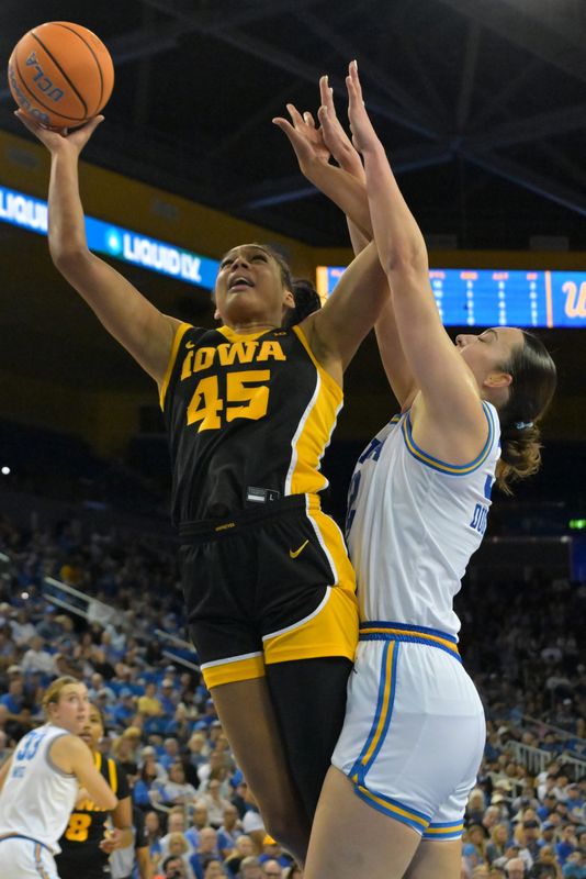 Feb 1, 2026; Los Angeles, California, USA; Iowa Hawkeyes forward Hannah Stuelke (45) drives past UCLA Bruins forward Angela Dugalic (32) in the second half at Pauley Pavilion presented by Wescom Financial. Mandatory Credit: Jayne Kamin-Oncea-Imagn Images