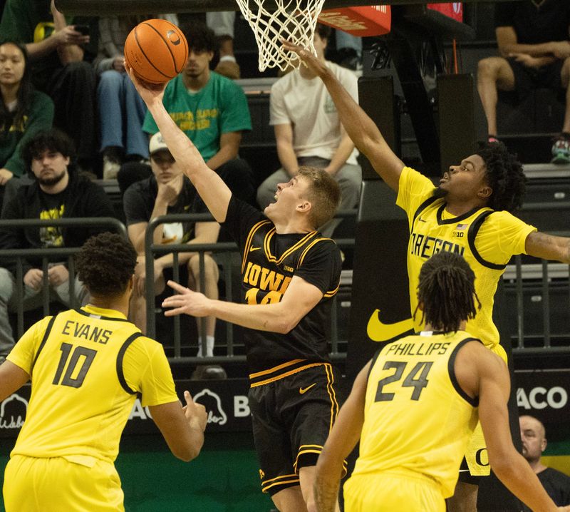 Oregon men basketball Iowaâ€™s Bennett Stirtz, center, shoots a reverse layup between Oregonâ€™s Kwame Evans Jr., left, Jamari Phillips and Takai Simpkins during the second half at Matthew Knight Arena in Eugene Feb. 1, 2026.