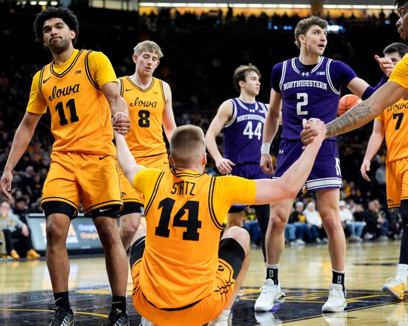 Iowa guard Kael Combs (11) helps up Iowa guard Bennett Stirtz (14) during a basketball game against the Northwestern Wildcats Feb. 8, 2026 at Carver-Hawkeye Arena in Iowa City, Iowa.