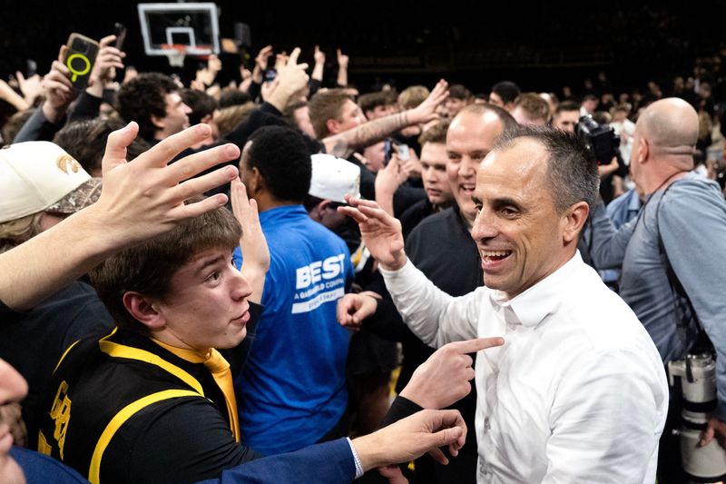 Iowa head coach Ben McCollum celebrates after Iowa fans stormed the court following the Hawkeyes win over the Nebraska Cornhuskers 57-52 Feb. 17, 2026 at Carver-Hawkeye Arena in Iowa City, Iowa.