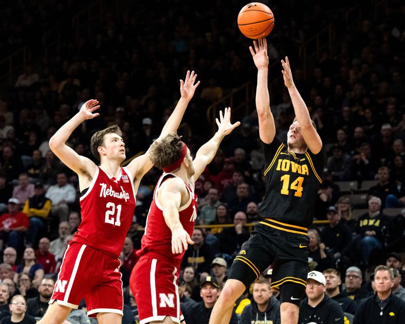 Iowa guard Bennett Stirtz (14) shoots the basketball as Nebraska forward Pryce Sandfort (21) and Nebraska guard Sam Hoiberg (1) defend on Feb. 17, 2026 at Carver-Hawkeye Arena in Iowa City, Iowa.