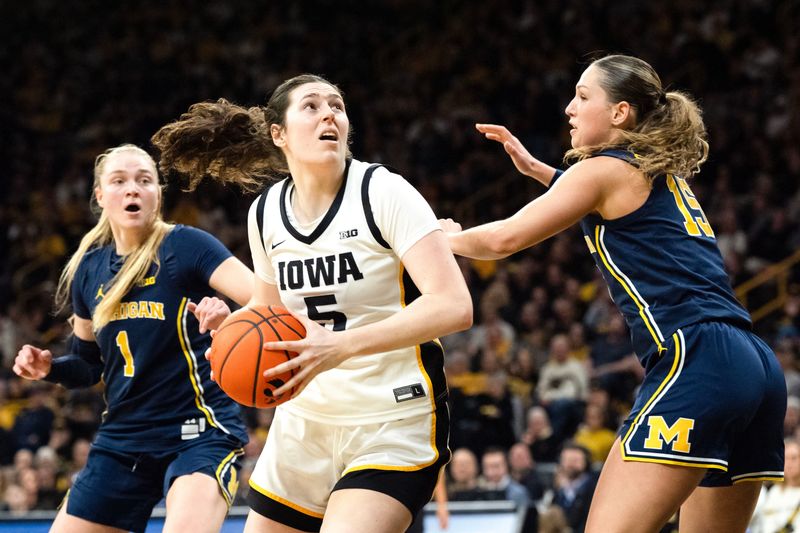 Iowa center Ava Heiden (5) turns toward the basket as Michigan forward Ashley Sofilkanich (15) and Michigan guard Olivia Olson (1) defend Feb. 22, 2026 at Carver-Hawkeye Arena in Iowa City, Iowa.