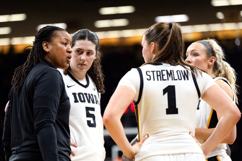 Iowa assistant coach Lasondra Barrett huddles with Iowa’s Ava Heiden (5), Taylor Stremlow (1) and Kylie Feuerbach (4) during a game against the Illinois Fighting Illini Feb. 26, 2026 at Carver-Hawkeye Arena in Iowa City, Iowa.