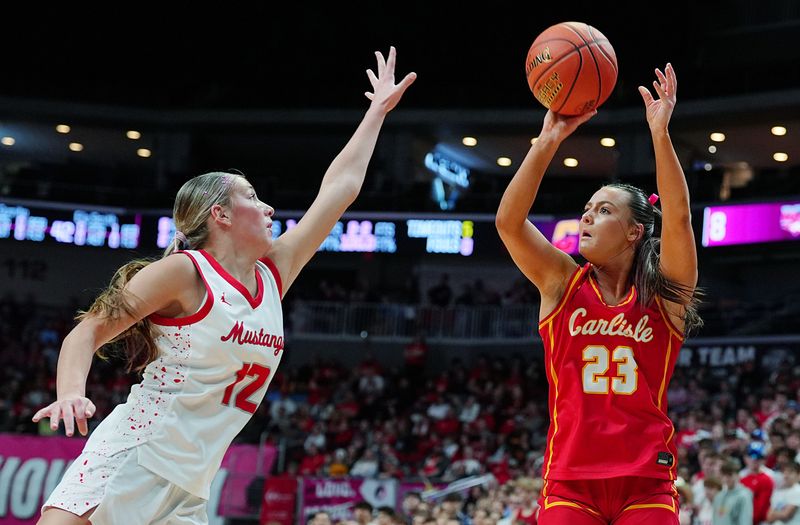 Carlisle Macy Comito (23) takes a three-point shot over Dallas Center-Grimes forward Ava Smid (12) during the first quarter in the 4A girls high school state basketball championship game on March 7, 2026, at Casey’s Center in Des Moines, Iowa.