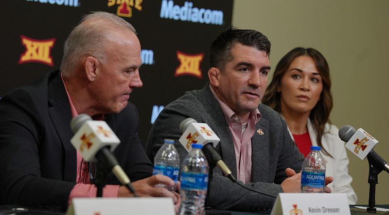 Iowa State new men’s wrestling head coach Brent Metcalf speaks as new wrestling director Kevin Dresser and new women wrestling head coach Alli St.John look on during a press conference at Hilton Coliseum on April. 16, 2026, in Ames, Iowa