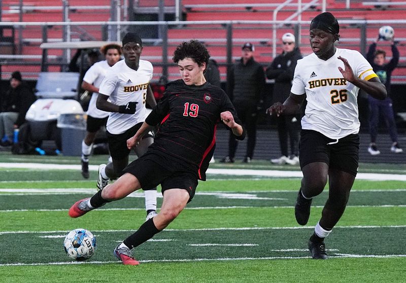 Ames striker Samuel Sadow (19) fires off a shot as Des Moines Hoover's Joshua Musengo (26) closes in on him during the first half of the Little Cyclone boys soccer team's 2-1 win over the Class 3A No. 3 Huskies at Ames High Stadium on May 1 in Ames, Iowa. Sadow scored one goal against Hoover and he is starting to emerge as a big threat on offense for Ames.