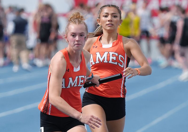 Ames’ Angelica Attinger and Brenna Van Cleave exchange baton during 4A girls 4x400 meter relay in the final day of the Iowa state high school co-ed track and field at Drake Stadium on May 23, 2026, in Des Moines, Iowa.