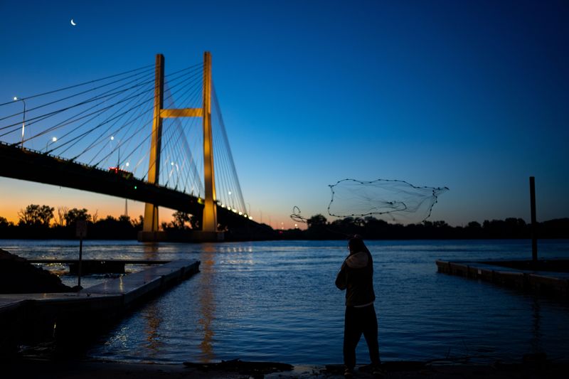 Justin Manning of Burlington throws a net to catch bait fish before sunrise, June 12, 2026, in Burlington, Iowa.