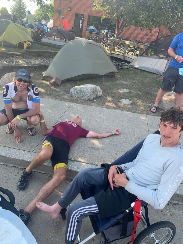 Peter Wood, left, and father John take a break after a grueling day on RAGBRAI 2026. The cross-state ride is one of several the two have taken to let Peter, who has cerebral palsy, experience the world.