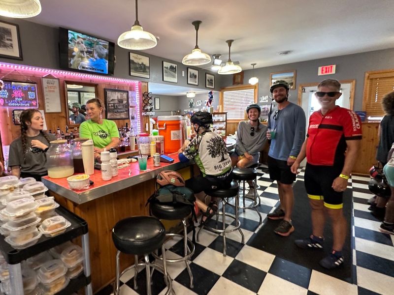 Gianna Pitcherello and Jessica McKinney work behind the counter at Niland's Cafe in Colo, serving happy RAGBRAI riders Catherine McConnell of Ankeny, Lindsay and John Hill of St. Augustine, Florida, and Tyler Penniman of St. Paul, Minnesota, on Wednesday, July 22, 2026.