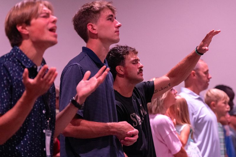 Jon Cardo, center, and other congregants sing worship songs Aug. 2, 2026 at The Acreage Church in West Union, Iowa.