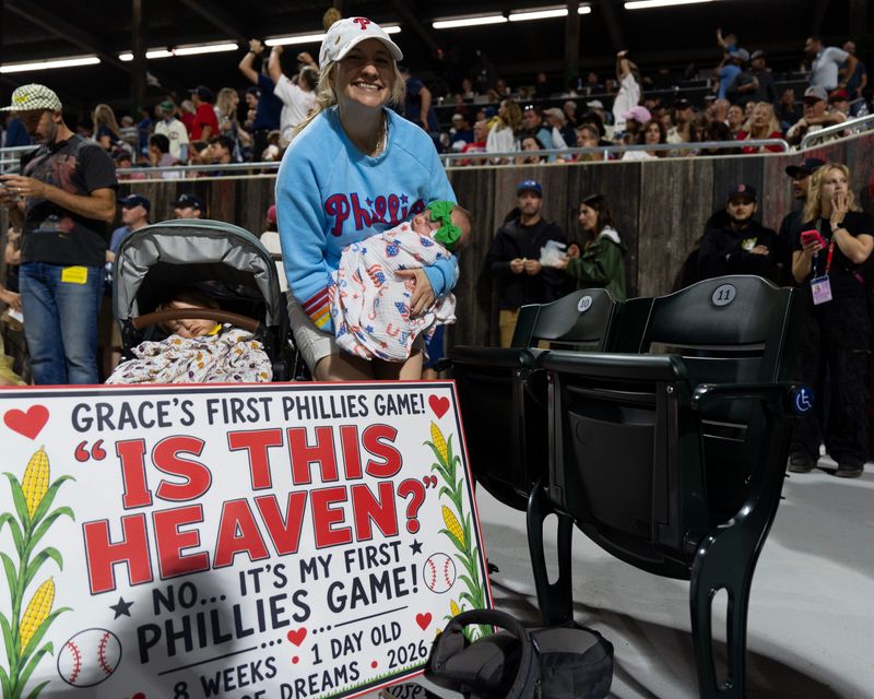 Philadelphia Phillies fan Amber Rowan holds her 8-week-old daughter Grace as her other daughter Brielle naps in the stroller Aug. 13, 2026 at the Field of Dreams in Dyersville, Iowa.