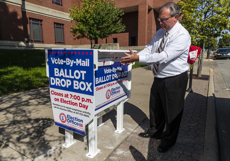 Sangamon County Clerk Don Gray shows the new secure ballot drop box along East Monroe Street outside the Sangamon County Complex, Thursday, Sept. 24, 2020, in Springfield. The 600-pound box, manufactured by Laserfab and Vote Armor, is bolted to the concrete and will be monitored by video 24/7 and emptied multiple times a day to ensure the integrity of ballot drop-off process.