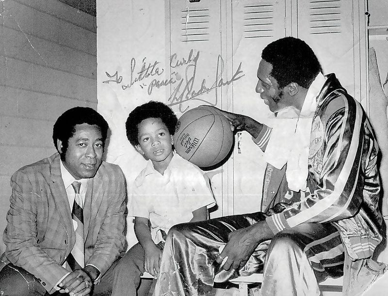 In this 1973 photo taken inside a locker room in Springfield, Meadowlark Lemon of the Harlem Globetrotters palms a basketball toward 8-year-old Curley "Boo" Johnson Jr. of Peoria, here sitting next to his father, Curley Johnson Sr. The elder Johnson played for and against the Trotters; his son played more than 4,000 games with the team. The photo is autographed by Lemon, who wrote, "To Little Curley. 'Peace.' Meadowlark."