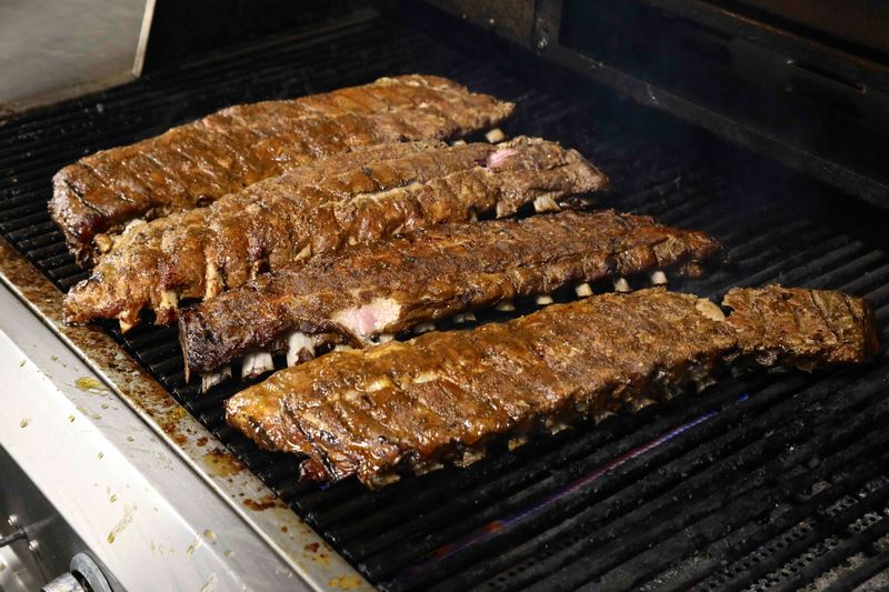 Slabs of smoked pork ribs warming on the grill Wednesday, May 12, 2021, at Smokin’ Coop BBQ in Belvidere.