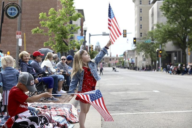 Ty Setter, left, 7, and his sister Ella Setter, 4, both of Rockford, play with their flags while waiting for the start of the Memorial Day Parade Monday, May 31, 2021, in downtown Rockford.