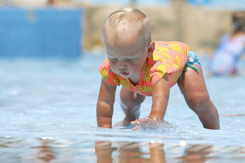 One-year-old Everlynn Young of Poplar Grove crawls in the shallow end of a pool Monday on opening day at Six Flags Hurricane Harbor in Rockford.