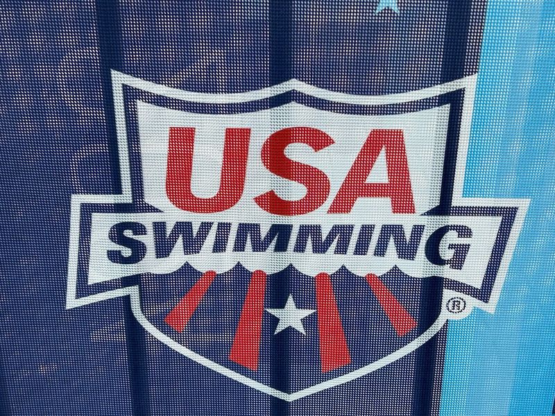 The logo of USA Swimming on a barricade along Georgia Street.