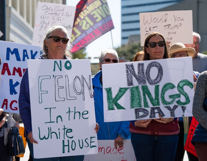 Two federal employees stand with signs protesting President Trump being in office. About 150 protested on the steps of the Duval County Courthouse Monday February 17, 2025 in downtown Jacksonville, Fl. as part of the Northeast Florida President’s Day Rally. They focused on Trump’s days in office, wanting to end mass deportations, limit Elon Musk’s overreach, resist fascism and protested Project 2025 among other issues. [Doug Engle/Florida Times-Union]