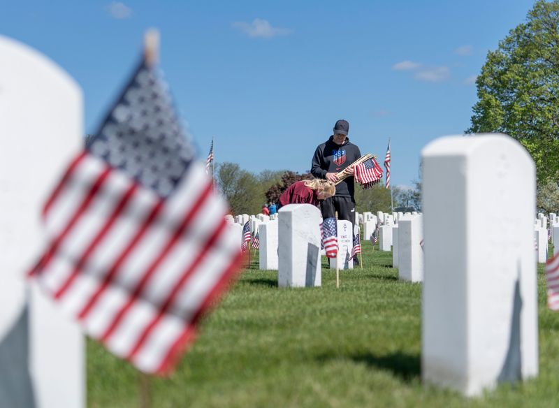Craig Charlton and his 8-year-old Kayley Charlton place flags at gravesites for the VA Memorial Day ceremony at Wood National Cemetery on Saturday May 24, 2025 in Milwaukee, Wis.