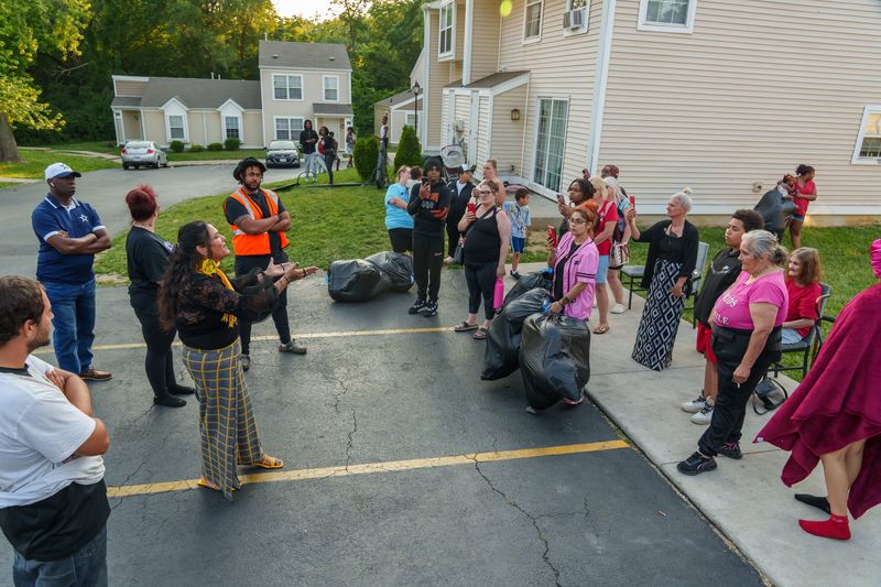 Tina Foley, in yellow scarf, an ordained minister and anti-violence activist, son Jordan Foley, in orange vest, a member of the Chicago Peacekeepers Program, and Pastor Alvin Riley, far left in white hat, of Sovereign Grace Missionary Baptist Church, lead a vigil Tuesday, June 10, 2025 for 12-year-old shooting victim Jayden Morris at the apartment complex where he was shot June 4 on Lehman Road in Peoria.