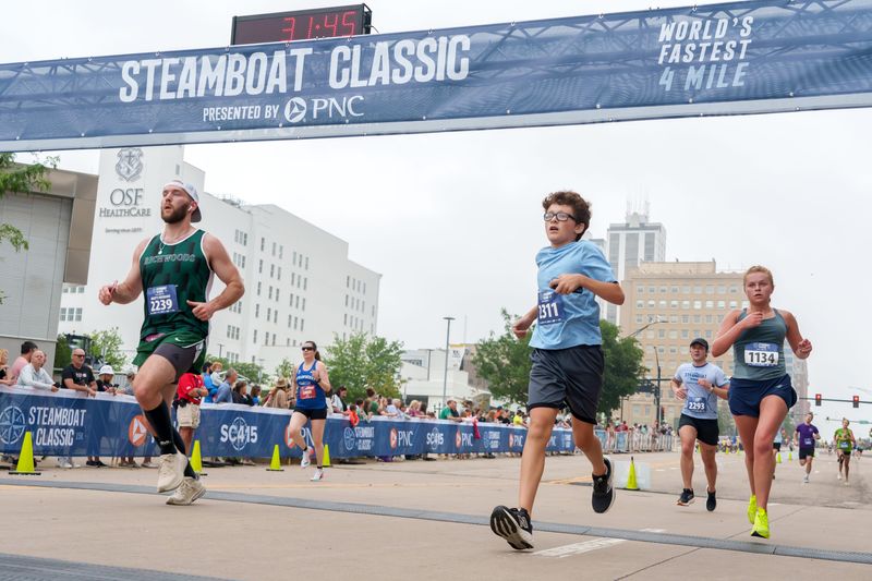 Runners cross the finish line at the bottom of Main Street during the 51st Steamboat Classic road races Saturday, June 14, 2025 in Downtown Peoria.