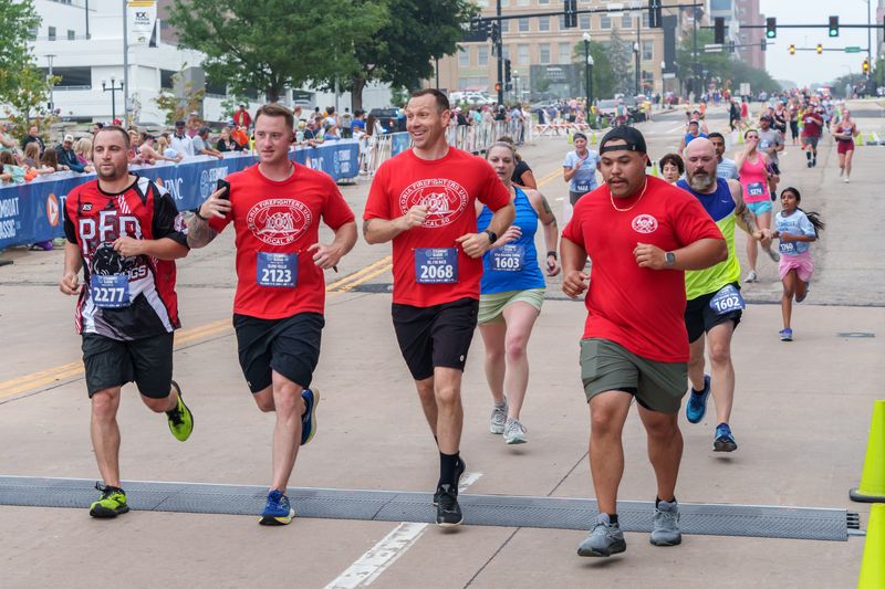 A quartet of Peoria firefighters finish the 51st Steamboat Classic 4-Mile race together Saturday , June 14, 2025 in Downtown Peoria.
