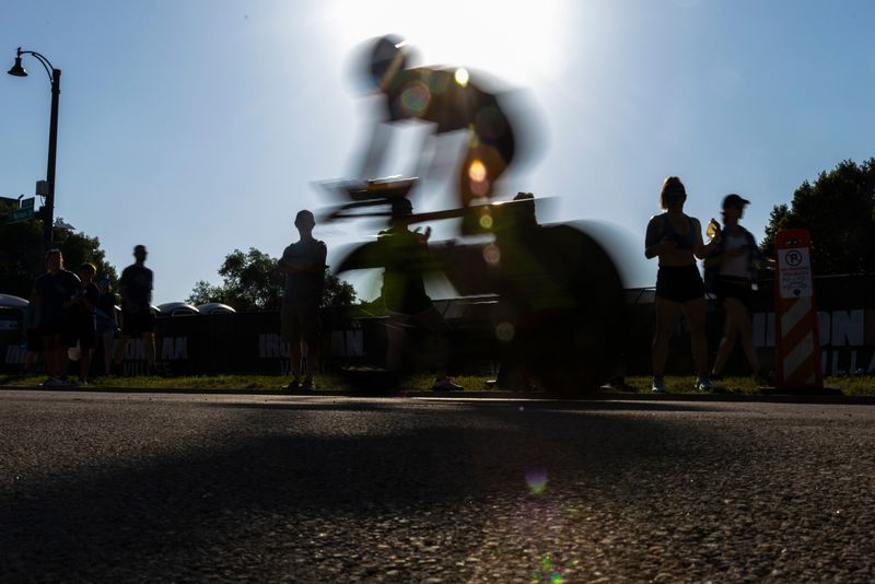 Bikers zoom by onlookers Sunday, June 22, 2025, during IRONMAN 70.3 Rockford in downtown Rockford.