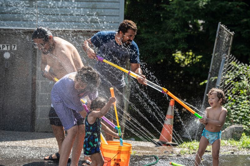 Alex Marin, Sam Medina, Madalyn Delossantos, 11, and Medina's children Leo-Wyatt, 4, and Mikey, 2, cool off with water toys and a sprinkler during a scorching afternoon in Yonkers June 23, 2025. Over the next two days, heat index values are forecasted to reach 107 degrees as a heat wave envelops much of the East Coast.