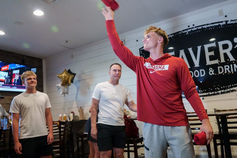 Dunlap senior and four-star college football recruit Mack Sutter, right, tosses University of Alabama shirts into the crowd after announcing his commitment to the SEC school during a gathering Thursday, June 26, 2025 at Weaver's Fresh Food & Drink in Peoria.