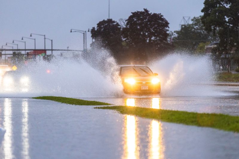 Cars drive through the flooded intersection on East State Street and North Trainer Road during a storm on July 10, 2025, in Rockford.