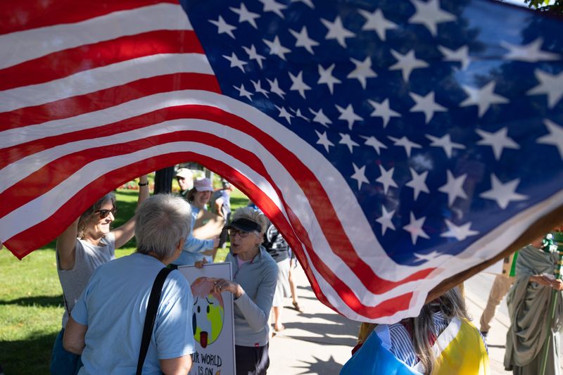 A protester holds an American flag along River Avenue in Holland, with others gathering in the background, during the "Good Trouble Lives On" protest July 17.