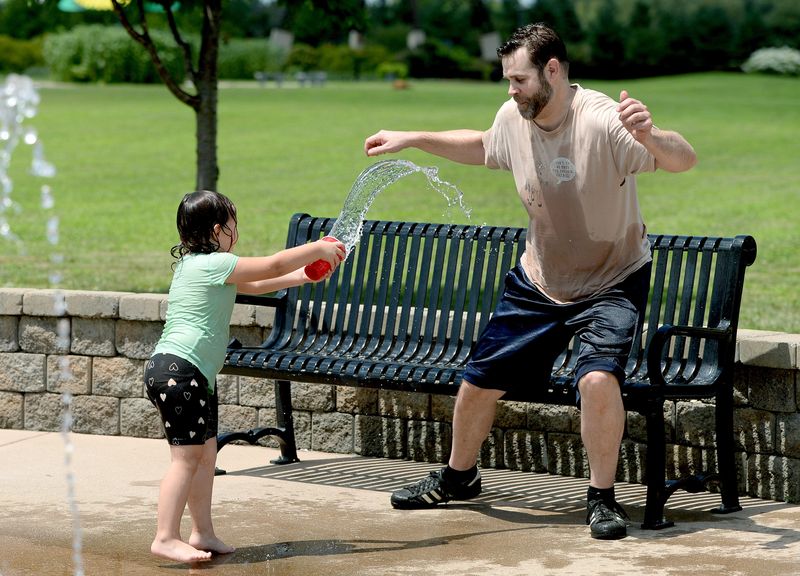 Cassidy Hink-Furrell, 4, left, cools down family friend Matthew Gustin, both of Springfield, at a splash pad at Southwind Park on July 23, 2025, in Springfield. Heat index values were expected to rise to 110-115 degrees on July 23 and July 24 during a heat wave.