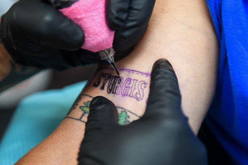 Missouri tattoo artist Leo Wilson does a Sturgis tattoo for Larry Plachecki of Minnesota on Monday, Aug. 4, 2025, at Rosini Gypsy Tour Tattooing in Sturgis, South Dakota. Plachecki states that this is his second Sturgis tattoo that he’s gotten during the annual rally.
