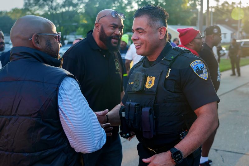 Peoria Police Chief Eric Echevarria greets men who gathered Monday, Aug. 25, 2025 at the front entrance to Manual High School in Peoria. Dozens of men lined the sidewalk to show support to students in the wake of a pair of nearby shootings last week.