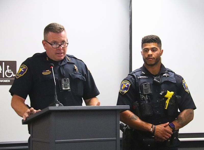 Pontiac Police Officer Tyren Mitchell, right, listens as Police Chief Dan Davis recognizes Mitchell for life-saving efforts Sept. 2, 2025, at the Pontiac City Council meeting.