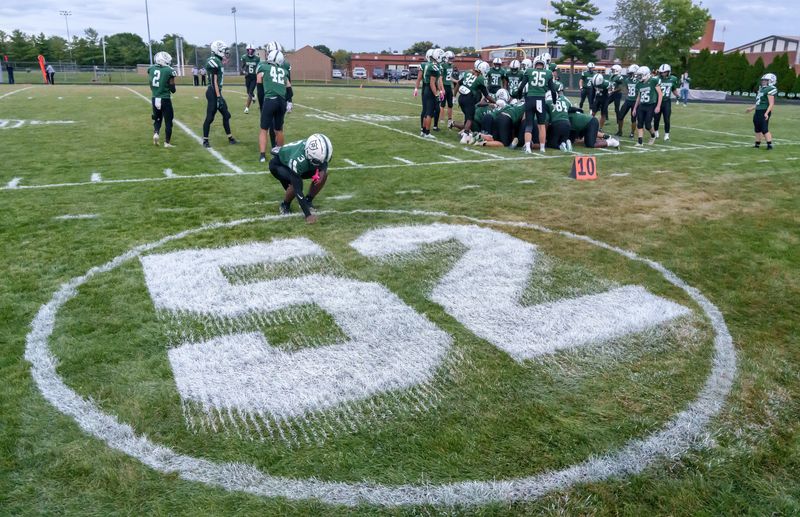 Richwoods' Terice Alexander touches a large jersey number 52 painted on the field for teammate Santonio Wallace, who drowned in April, before the start of the Knights' Week 2 high school football game Friday, Sept. 5, 2025 at Richwoods High School. The Knights defeated the Rams 28-14.