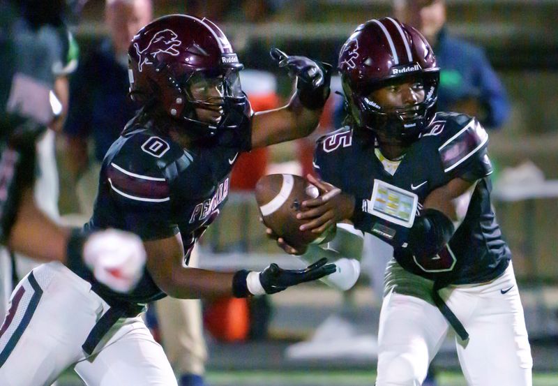 Peoria High quarterback Breon Green, right, hands off to running back DeTaurion Pollard in the second half of their Week 2 high school football game Friday, Sept. 5, 2025 at Peoria Stadium. The Lions defeated the Irish 58-31.