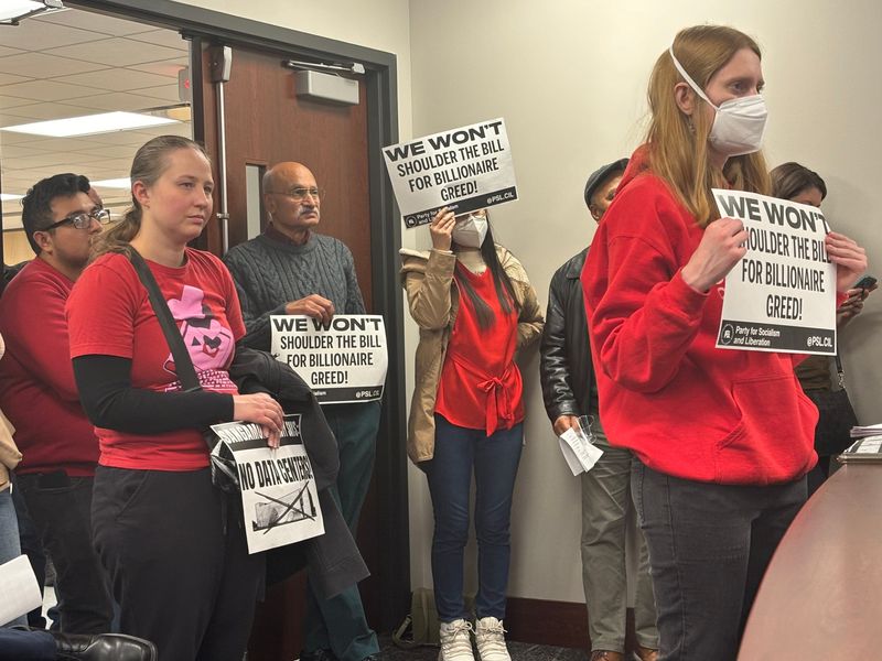 A number of people at the Nov. 10, 2025, Sangamon County Board meeting hold signs in opposition of a proposed data center in Talkington Township.