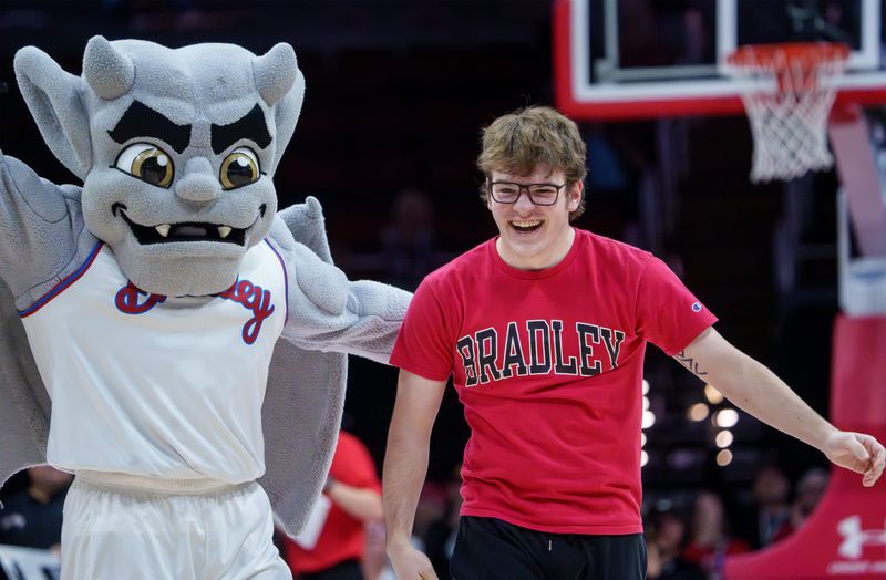 Bradley sophomore civil engineering student Max Debaun of Batavia celebrates with mascot Kaboom! after sinking a layup, a three-pointer and a half-court shot for an Alexander's Steakhouse food voucher in a contest at the basketball game between Bradley and UMass Lowell on Wednesday, Nov. 19, 2025 at Carver Arena in Peoria.