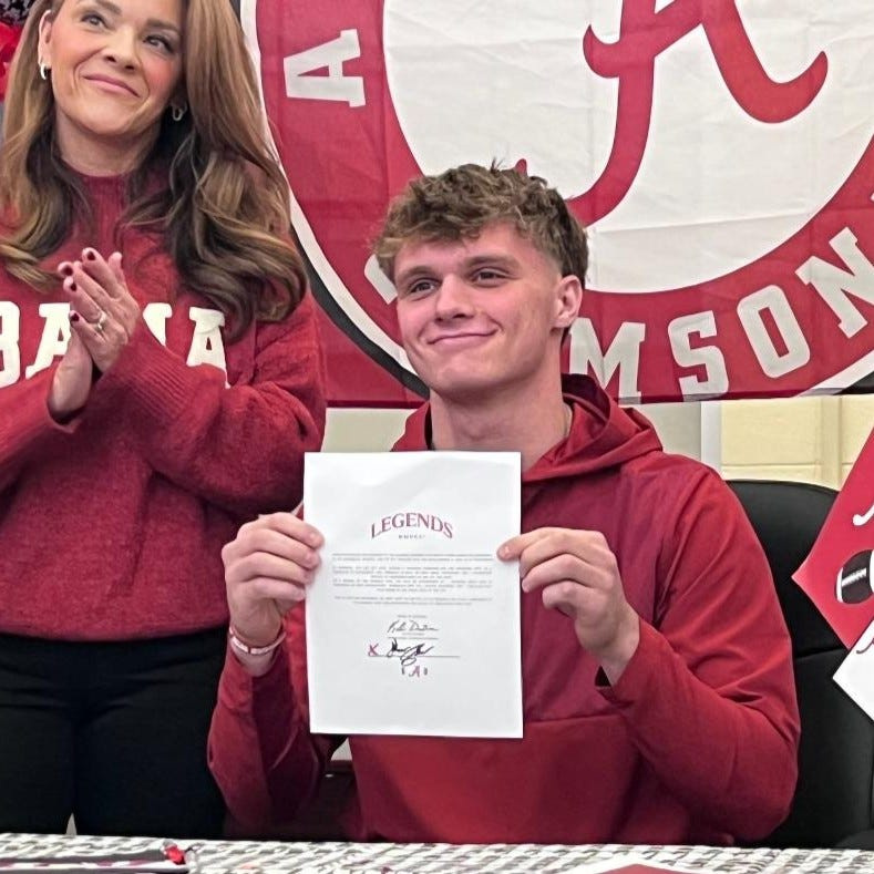 Dunlap senior Mack Sutter smiles as he holds up his signed athletic grant-in-aid agreement with Alabama with his mom, Tracy Sutter, clapping in the background. The No. 1-ranked Illinois high school football player made his June commitment to the Crimson Tide official on Dec. 3, 2025.
