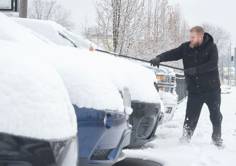 Michael Hand, Sales Manager at Stark Auto Mall in Perry Township, cleans snow off lot vehicles. Tuesday, December 2, 2025.