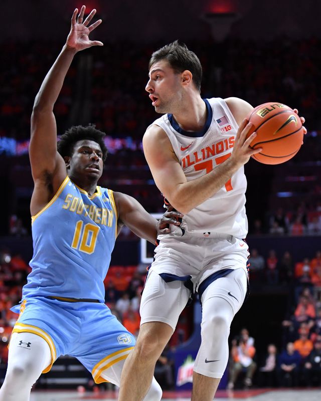 Dec 29, 2025; Champaign, Illinois, USA; Illinois Fighting Illini guard Mihailo Petrovic (77) drives to the basket as Southern University Jaguars guard Michael Jacobs (10) defends during the first half at State Farm Center. Mandatory Credit: Ron Johnson-Imagn Images