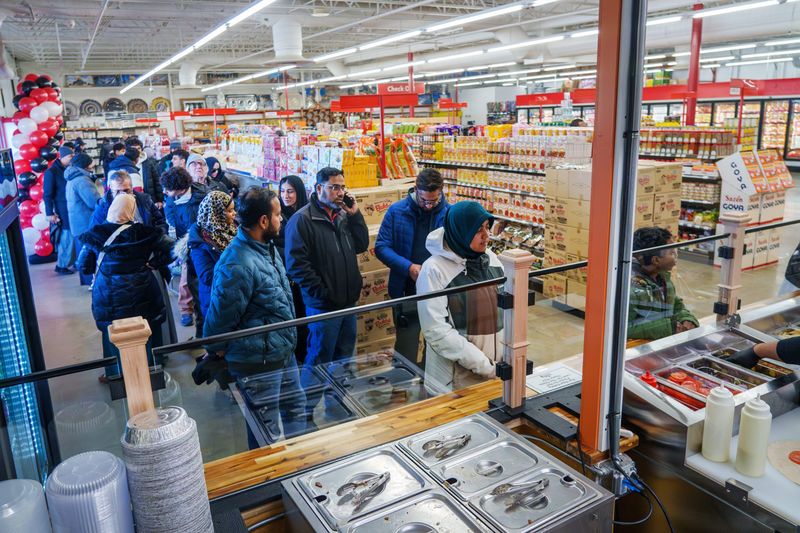 A line of customers wait for their orders from the new carryout version of Curly Shawarma inside the Haddah Supermarket at 2800 W. Townline Road in Peoria.