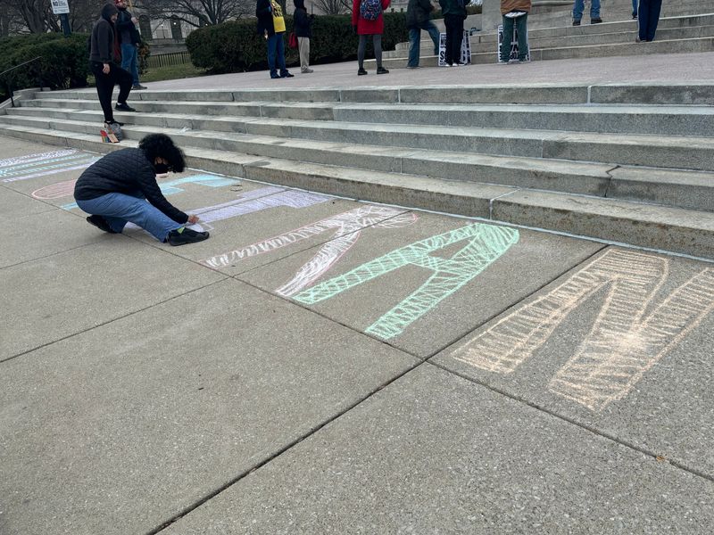 Several people chalked "Out of Iran" on the sidewalk in front of the Illinois Capitol at a No War with Iran rally on March 2, 2026. The rally was put on by Land of Lincoln Democratic Socialists of America, 50501 Springfield and the Party for Socialism and Liberation - Central Illinois.
