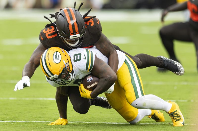 Sep 21, 2025; Cleveland, Ohio, USA; Cleveland Browns linebacker Devin Bush (30) tackles Green Bay Packers running back Josh Jacobs (8) during the third quarter at Huntington Bank Field. Mandatory Credit: Scott Galvin-Imagn Images