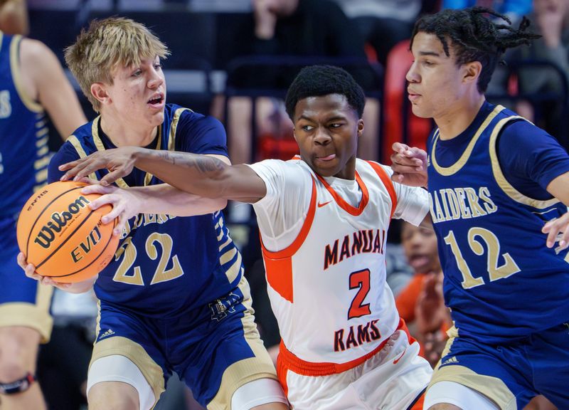 Manual's Tahj Tolliver (2) tries to take the ball from Quincy Notre Dame's Robbie Reed (22) in the first half of their Class 2A boys high school basketball state championship game Saturday, March 14, 2026 at the State Farm Center in Champaign. The Rams defeated the Raiders 60-55 for the title.