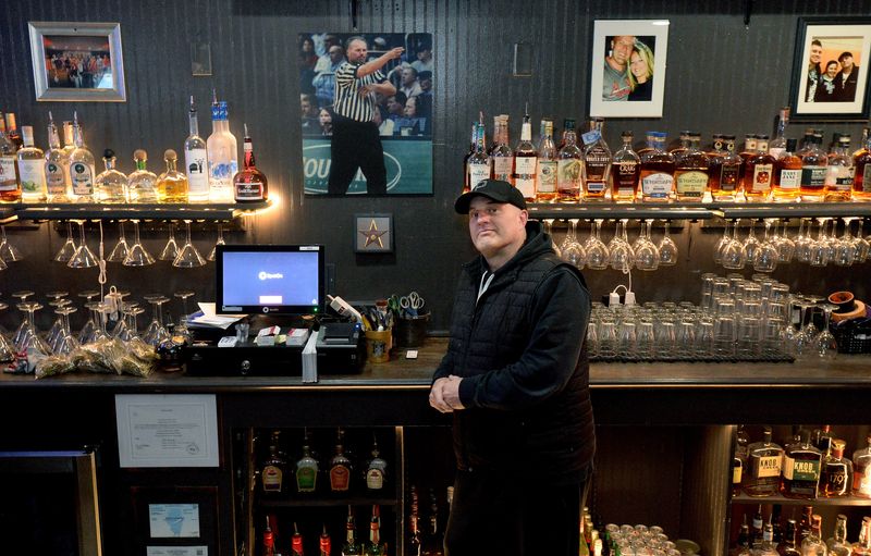 Josh Snodgrass, a co-owner of Mick and Mary's, poses for a photo under a picture of his father at the restaurant on Monday, March 16, 2026, in Thayer. The restaurant recently reopened after months of renovations.