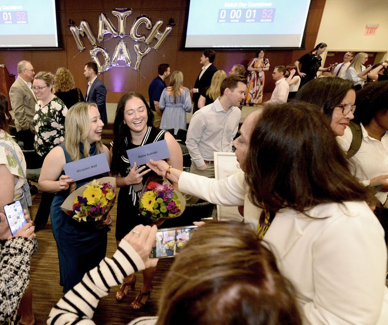 SIU School of Medicine students Micaylen Wolf of Harrisburg, center left, and Blaine Bulinski of Oreana, center right, hold the envelopes containing their matches as they get photographed during a matching ceremony at the Nelson Family Auditorium, Memorial Learning Center Friday, March 20, 2026.