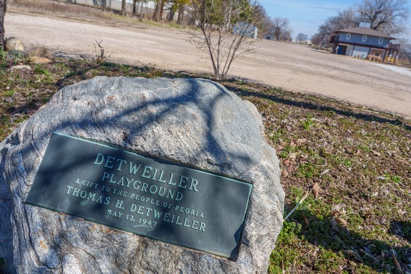 A plaque affixed to a large boulder marks the designation of Detweiller Playground as a gift to Peoria by Thomas H. Detweiller in 1947.